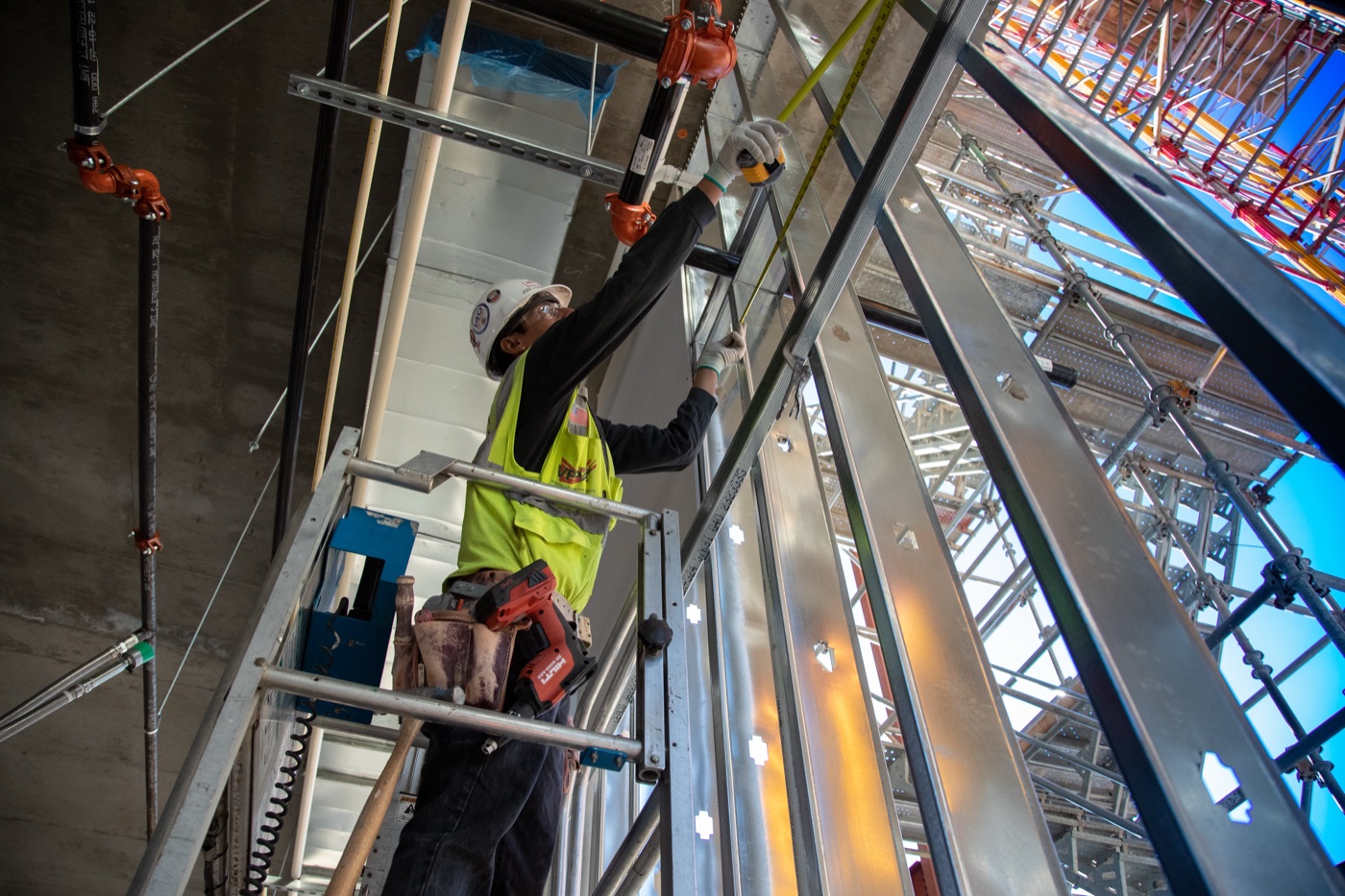 Tradesman on a scaffold measuring steel stud framing
